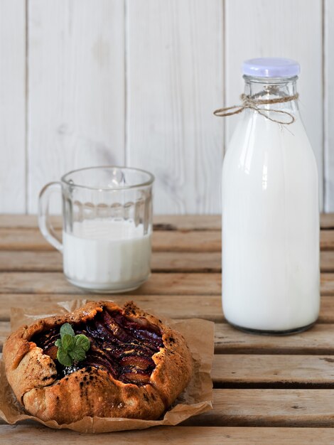 Galette with plums and bottle with milk