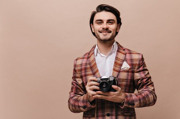 Gallant young brunette-haired gentleman in plaid blazer and stylish shirt looking straight and holding camera