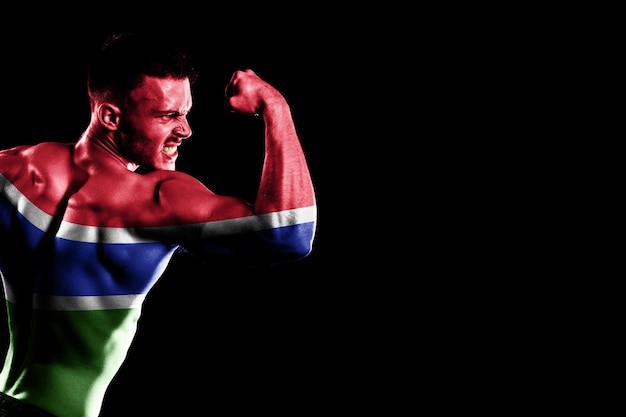 Gambia flag on handsome young muscular man black background