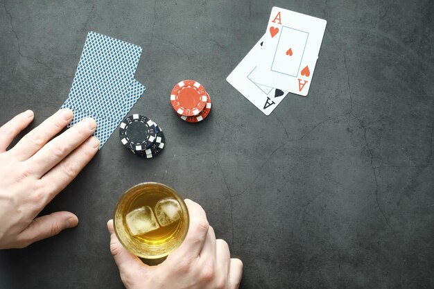 お金のためのギャンブルカードゲーム。テキサスホールデムポーカー。手持ちのカード、トランプ、グラスに入ったアルコールのカードのデッキ。