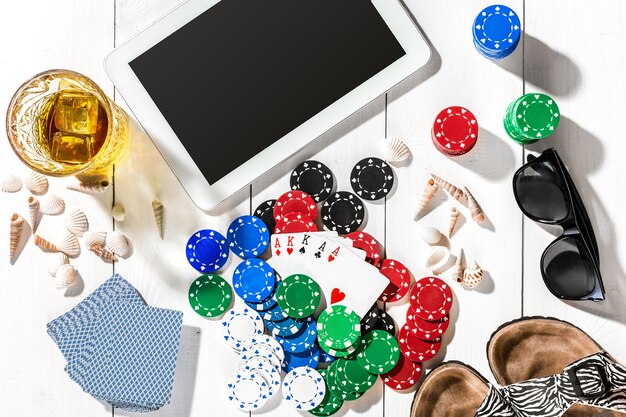 Gambling. Poker chips, cards and the dice nearby tablet on white wooden table. Top view. Copyspace. Poker. Summer