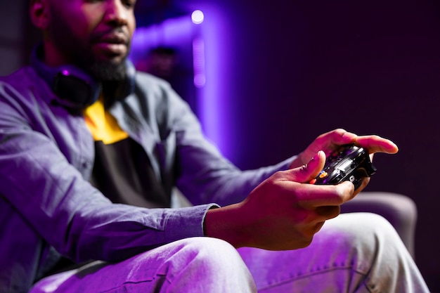 Gamer on couch using controller and headphones to play game at home close up