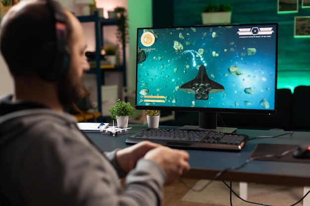 Gamer using headphones and joystick to play video games on computer. Man playing with controller and audio headset for online gaming. Player having fun with equipment to play games.