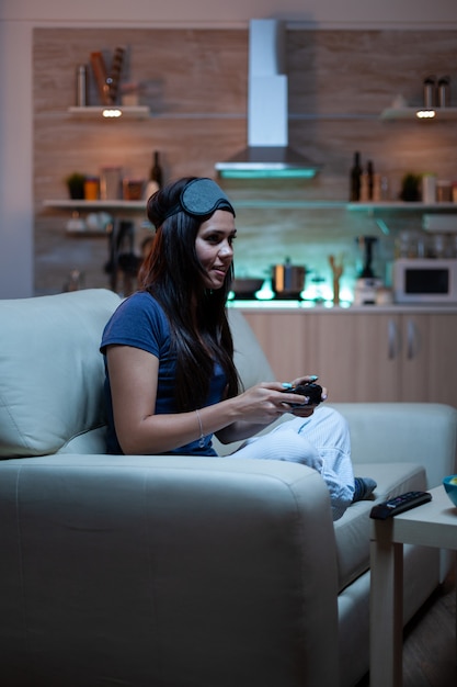 Free photo gamer woman playing video games on console using controller and joysticks sitting on couch in front of tv