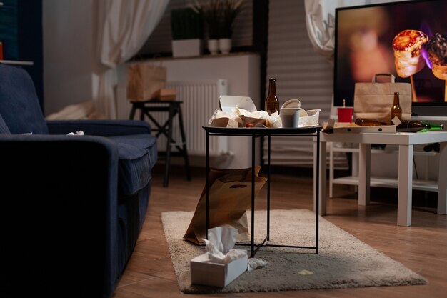 Garbage table with empty beer drink bottle and food rubbish placed in living room