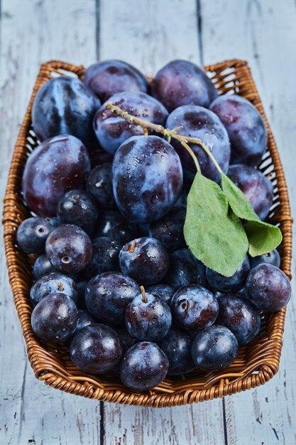 Garden plums on basket on blue.