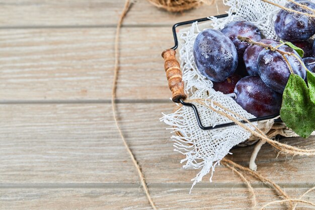 Garden plums in a basket on a wooden table. High quality photo