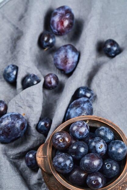 Garden plums in a bowl on gray tablecloth. High quality photo