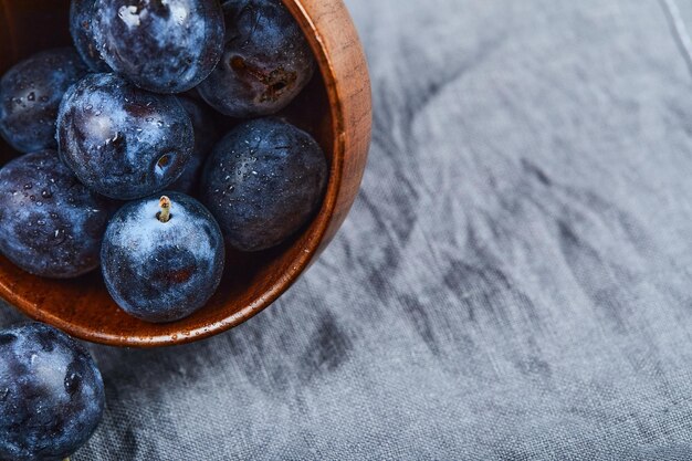 Garden plums in a bowl on gray tablecloth. High quality photo