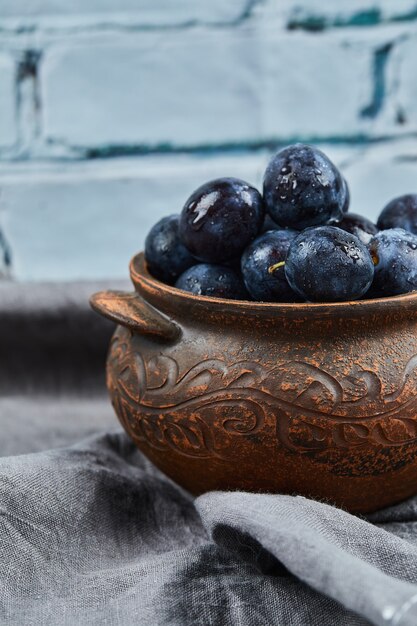 Garden plums in a bowl on gray tablecloth.