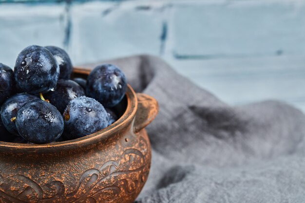 Garden plums in a bowl on gray tablecloth.