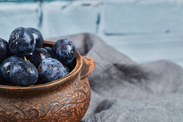 Garden plums in a bowl on gray tablecloth.