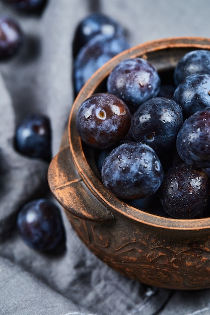 Garden plums in a bowl on gray tablecloth.