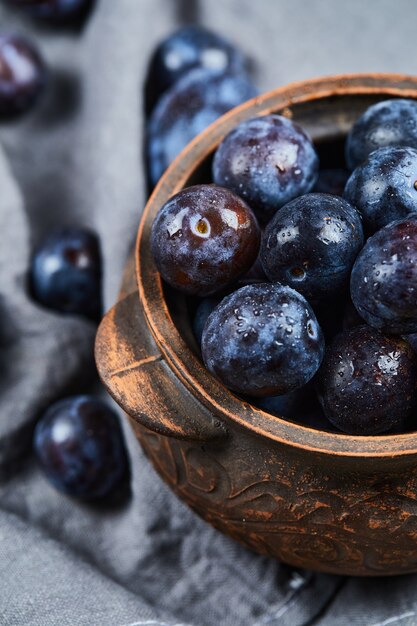 Garden plums in a bowl on gray tablecloth.