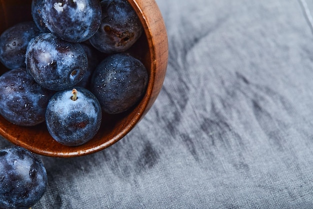 Garden plums on bowl on gray tablecloth.