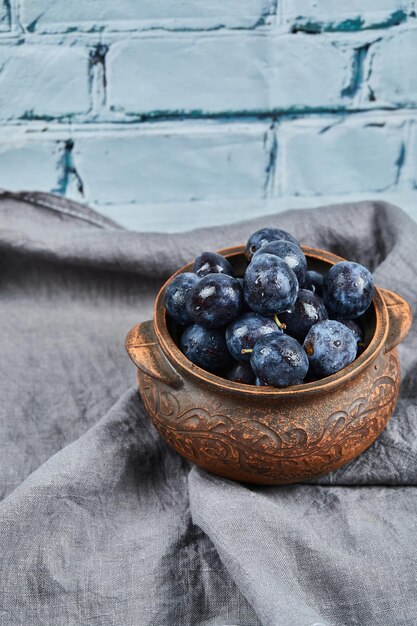 Garden plums on bowl on gray tablecloth.