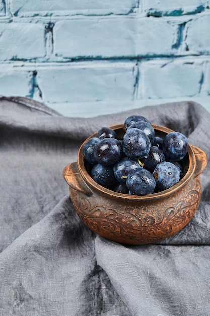 Garden plums on bowl on gray tablecloth.