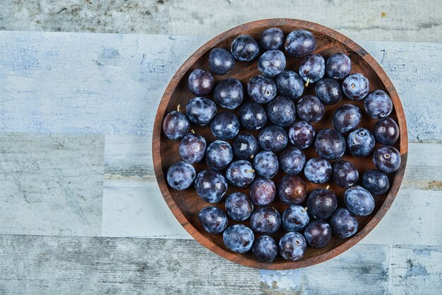 Garden plums in a plate on blue.