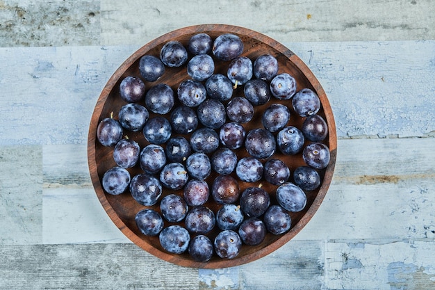 Garden plums on plate on blue.