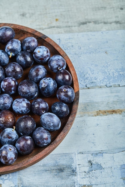 Garden plums on plate on blue.