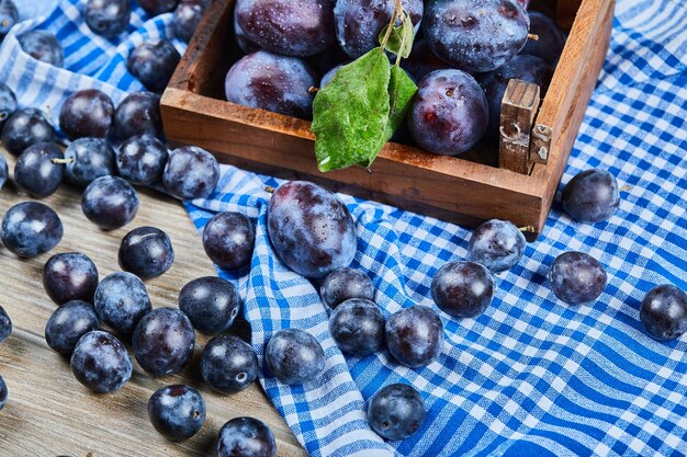 Garden plums scattered through wooden table.