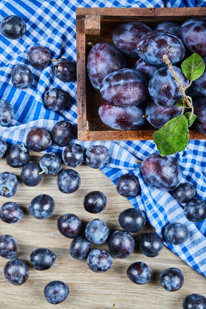 Garden plums scattered through wooden table.