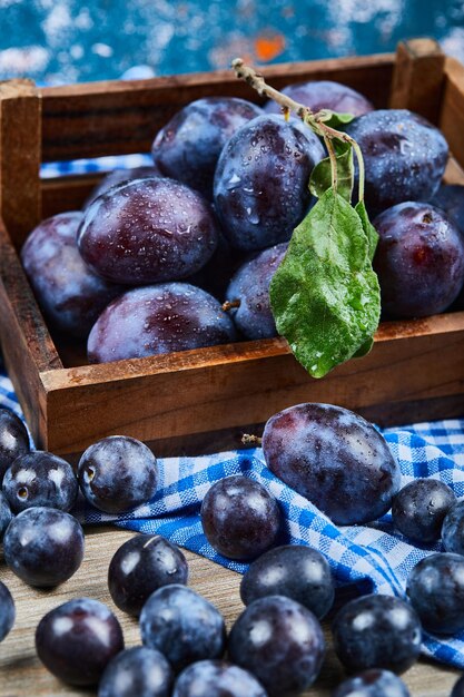 Garden plums scattered through wooden table.