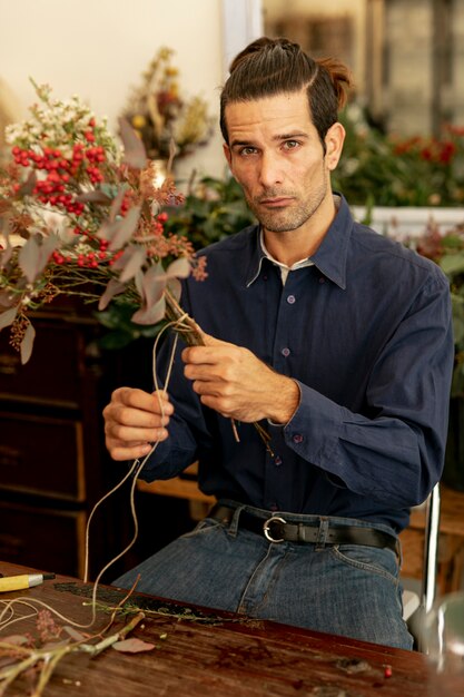 Gardener man with long hair cutting a rope