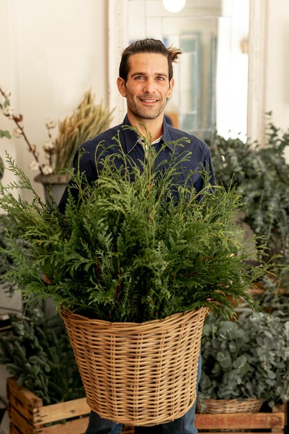 Gardener man with long hair holding a basket with leaves