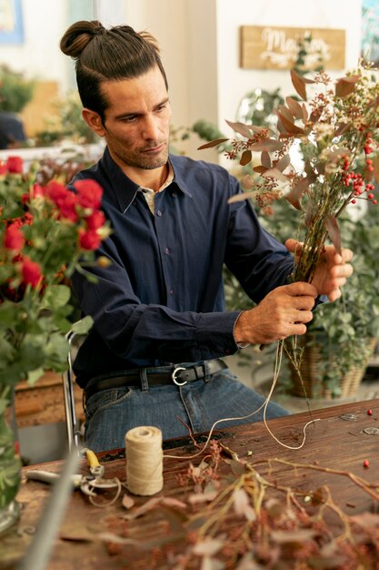 Gardener man with long hair holding bouquet of flowers