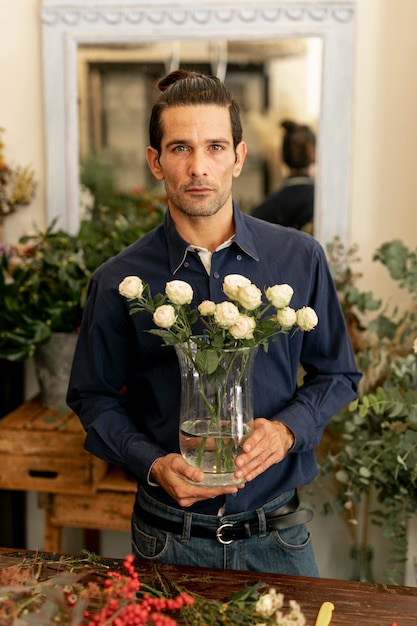 Gardener man with long hair holding flowers