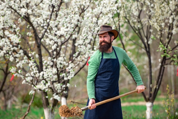 Садовник сажает весной сад бородатый мужчина садовник в городском саду рабочий экофермы