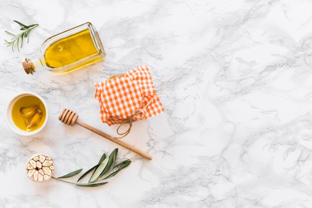 Garlic clove oil with jar on white marble backdrop