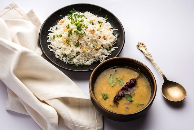 Garlic fried rice or pulav using basmati rice and lahsun, served with dal tadka over moody background, selective focus