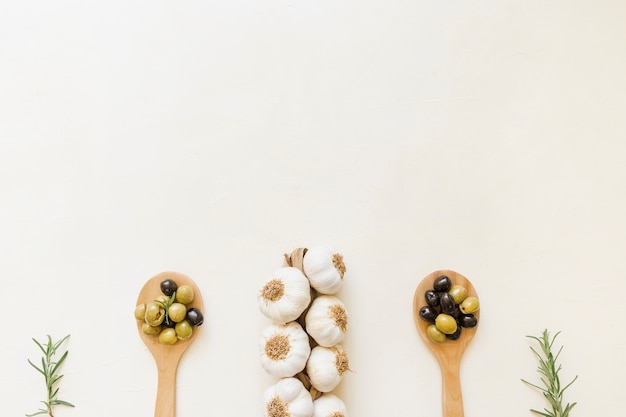 Garlic and olives in wooden spoons