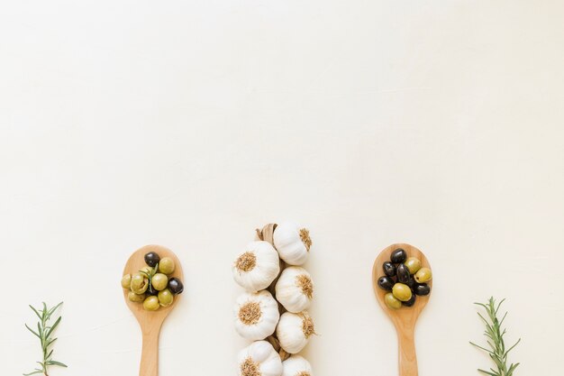 Чеснок и маслины в деревянных ложках