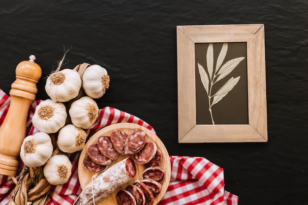 Garlic and sausage lying near frame and spices