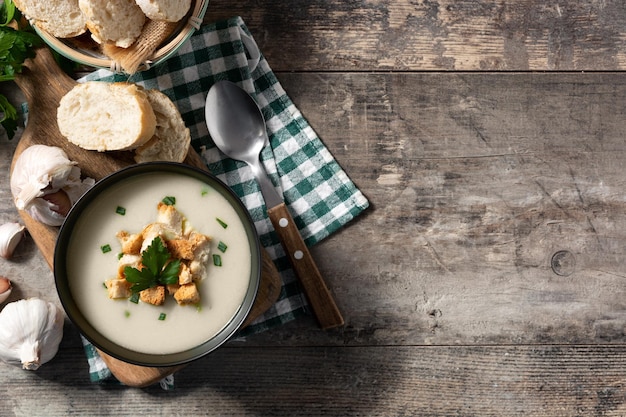 Garlic soup topped with croutons in bowl on wooden table