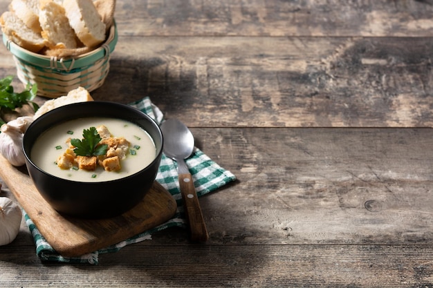 Free photo garlic soup topped with croutons in bowl on wooden table