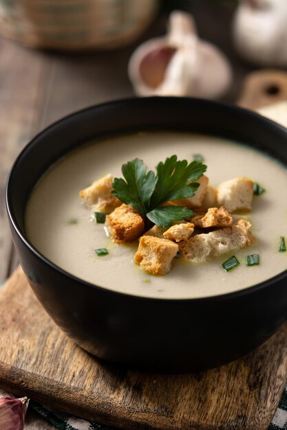 Free photo garlic soup topped with croutons in bowl on wooden table