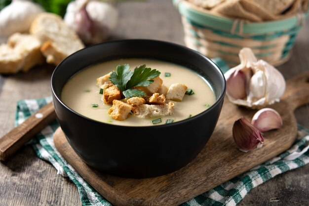 Garlic soup topped with croutons in bowl on wooden table
