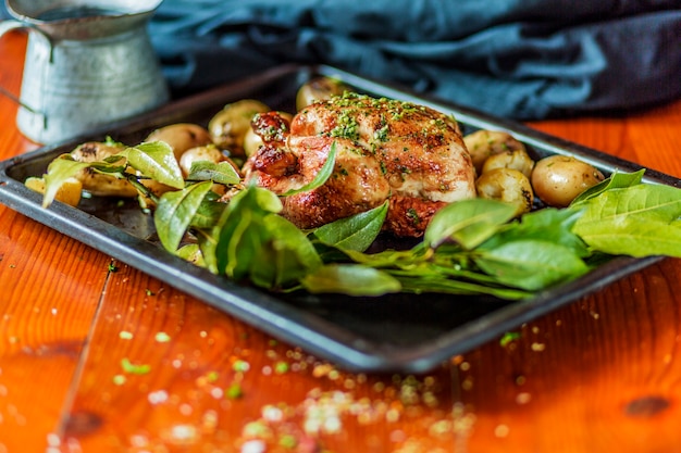 Garnish roasted turkey and potatoes with leaves in tray on wooden table