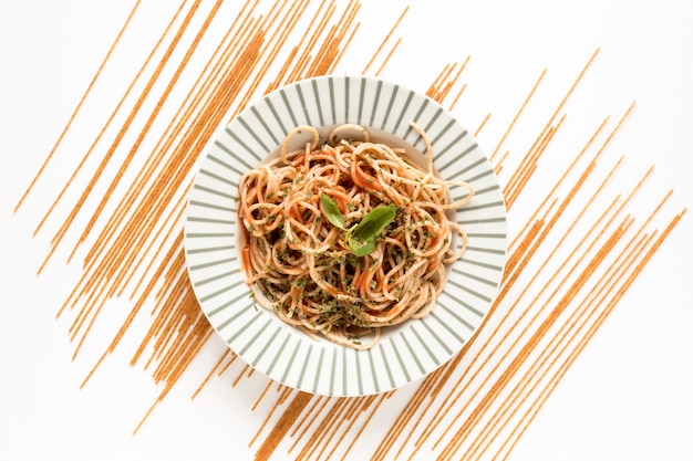 Free photo garnish spaghetti pasta with raw pasta on white surface