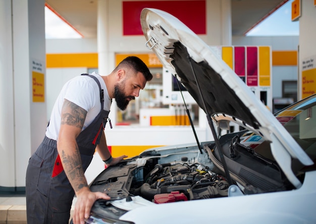 Foto gratuita lavoratore della stazione di servizio che si prende cura dell'auto del cliente