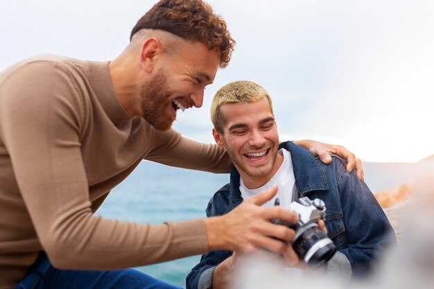 Gay couple on the beach with camera