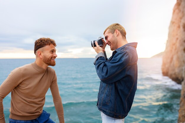 Gay couple on the beach with camera