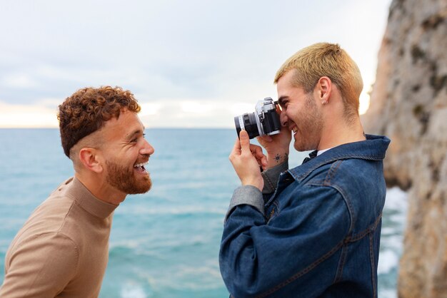 Gay couple on the beach with camera