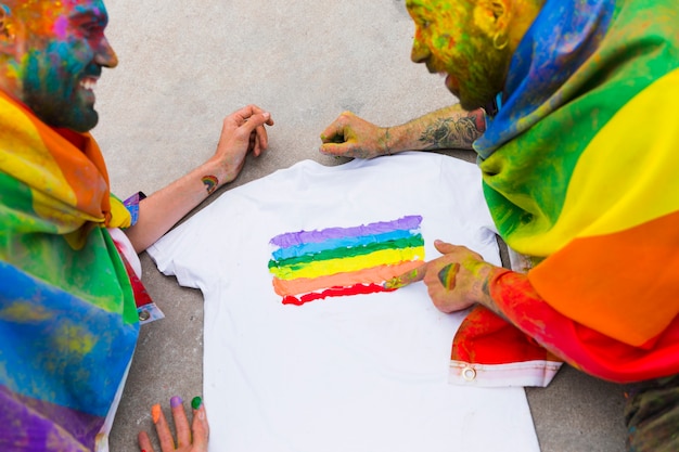 Gay couple drawing rainbow flag on t-shirt