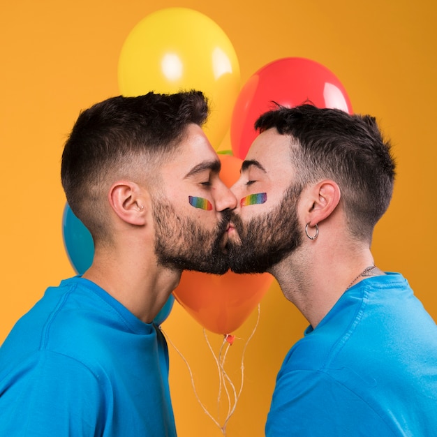 Gay couple kissing against colorful balloons