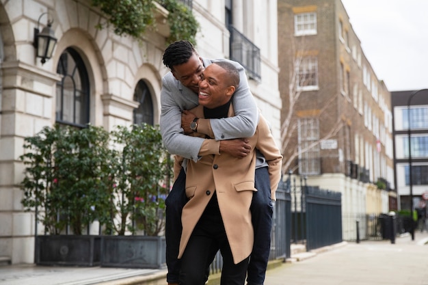 Free photo gay couple piggy back riding while happily out on a date